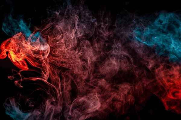 Dense multicolored smoke of blue and red colors on a black isolated background. Background of smoke vap