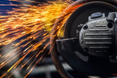 Bir genç adam kaynakçı bir beyaz eldiven değirmeni bir açı değirmeni atölyede metal, sinek tarafa kıvılcım. Araba tamir ve araba tamircisi kavramı