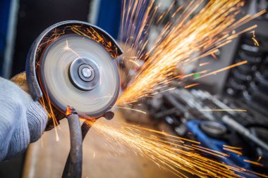 Bir genç adam kaynakçı bir beyaz eldiven değirmeni bir açı değirmeni atölyede metal, sinek tarafa kıvılcım. Araba tamir ve araba tamircisi kavramı