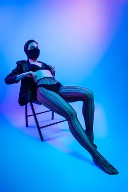 İçinde neon kadın sinema gece portresi. Yüksek moda modeli kız renkli parlak neon ışıkları Studio, ceket, iç çamaşırı ve pantolon güzel kadın portresi poz. 