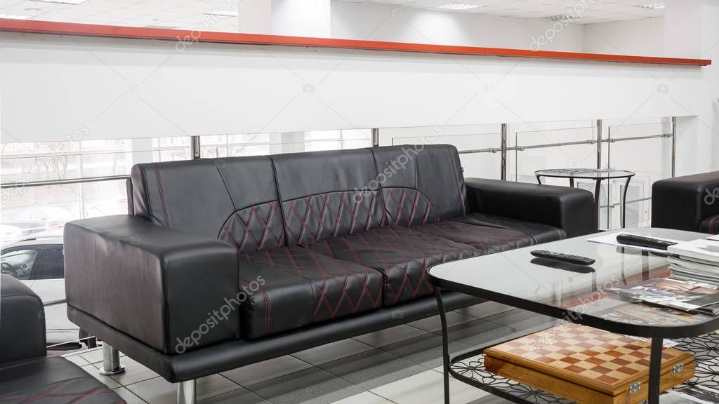 Living room interior for reception with handmade black leather sofas with white design of walls, ceilings, floor. Reception for guests in the office