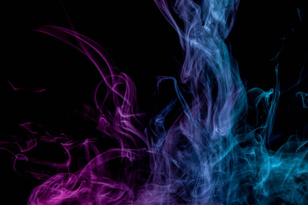 Abstract art colored pink and blue smoke on black isolated background. Stop the movement of multicolored smoke on dark backgroun