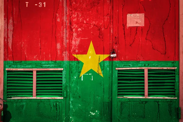 Close-up of old warehouse gate with national flag of Burkina Faso. Concept of  Burkina Faso export-import, storage of goods and national delivery of goods. Flag in grunge style
