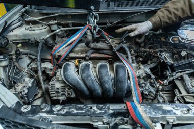 Pnömatik el ile vinç oto tamircisi kullanarak eski bir araba motor kurulumu Close-up. Otomatik mekanik motor kaldırmak için çalışmalarını