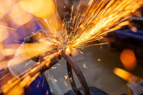 Bright orange and yellow sparks on a black background. A stream of bright sparks from metal cutting