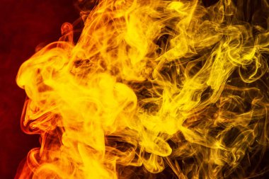 Donmuş soyut hareket patlama sarı ve turuncu siyah arka plan üzerine çok sayıda renk duman. Arka plandan vape duman