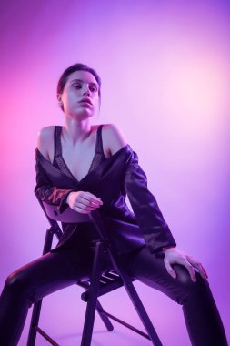 Çekici uzun saçlı kız, şık moda. Tasarım sanat kavramı. Yaratıcı renkli parlak neon portre. Güzel kız ceket ve sandalyeye poz underwewar. Neon kadın sinema gece portresi.