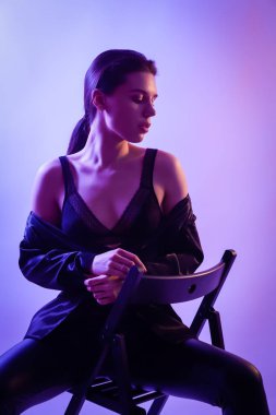 Çekici uzun saçlı kız, şık moda. Tasarım sanat kavramı. Yaratıcı renkli parlak neon portre. Güzel kız ceket ve sandalyeye poz underwewar. Neon kadın sinema gece portresi.