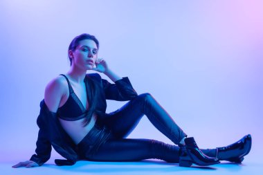 Yüksek moda modeli kadın stüdyoda poz moda t-shirt mavi ve pembe renkli parlak neon uv ışık içinde. Moda kavramı ve Zine kültür