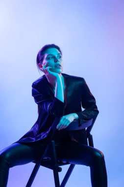 Studio poz yüksek moda model kadın moda ceket ve pantolon mavi ve pembe renkli parlak neon uv ışık içinde. Moda kavramı ve Zine kültür