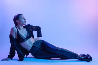 Yüksek moda modeli kadın stüdyoda poz moda t-shirt mavi ve pembe renkli parlak neon uv ışık içinde. Moda kavramı ve Zine kültür