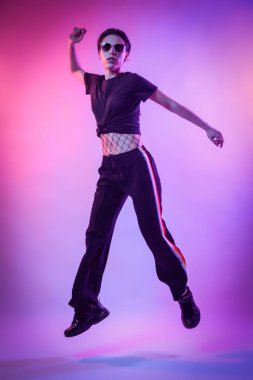 Studio poz yüksek moda model kadın moda tişört ve pantolon renkli parlak neon uv ışık, mavi ve pembe renkleri LGBT yaşamı içinde çizgili. Moda kavramı ve Zine kültür