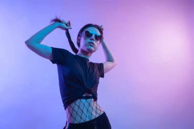 Studio poz yüksek moda model kadın moda tişört ve pantolon renkli parlak neon uv ışık, mavi ve pembe renkleri LGBT yaşamı içinde çizgili. Moda kavramı ve Zine kültür
