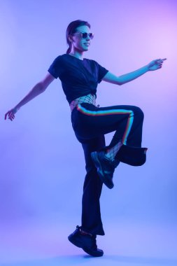 Studio poz yüksek moda model kadın moda tişört ve pantolon renkli parlak neon uv ışık, mavi ve pembe renkleri LGBT yaşamı içinde çizgili. Moda kavramı ve Zine kültür