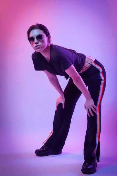 High Fashion model  woman in fashion t-shirts and pants with stripes in colors lgbt in colorful bright neon uv blue and pink lights, posing in studio. Fashion concept and Zine culture