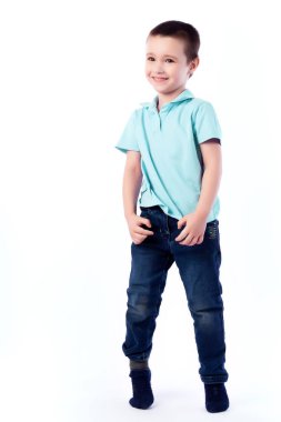 Mavi Jeans, koyu saçlı küçük boy gülümseyerek mavi polo t-shirt poz, gülerek mutlu bir şekilde beyaz bir arka planda bir fotoğraf stüdyosu izole. Mutlu neşeli güzel çocuk portresi