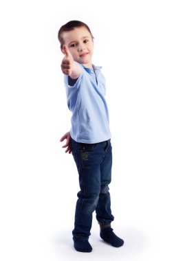 Koyu saçlı mavi jeans, mavi polo t-shirt poz içinde küçük boy gülümseyerek mutlu bir şekilde, gülüyor bir beyaz izole arka planda bir fotoğraf Studio sınıf parmağını gösterir. Mutlu neşeli güzel çocuk portresi