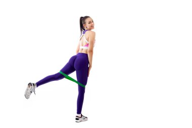 Ypung kadın at arabasıyla bir sportif mor kısa top ve spor salonu tozluk yapar lunges spor fitness lastik bantlar, Kanepeye ayakkabınla ileri tarafından streç bacaklar beyaz bir izole arka planda Studio 