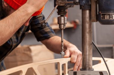 Ev onarım kavramları, yakın çekim. El sanatları marangozluk. Atölye çalışma masasında mobilyacının eller elektrik kullanarak bir ahşap tahta sondaj matkap