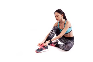 Stüdyoya beyaz izole bir arka planda zemin ve bağlama Ayakkabı oturan sportif kısa üst ve spor Tayt Genç bir kadın modeli 