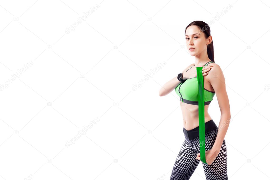A young woman model in a sporty clothes doing sport exercise on biceps with sport fitness rubber bands on a  white isolated background in studio