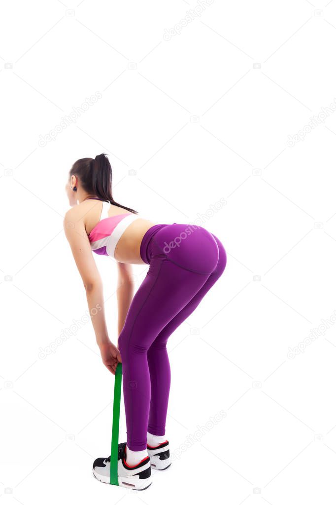 Sporty woman does  exercises and stretch on legs and buttons  with sport fitness rubber bands  on white background. Photo of muscular woman in sportswear on white background. Strength and motivation. 