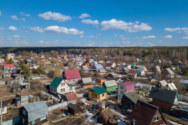 Aerial photography of a a cottage village with colorful houses, road, green trees and yards. Helicopter drone shot