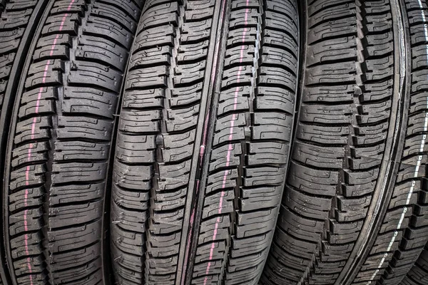 Car tires in a row on a shelf tire. Protector of automobile tires. A number of automobile tires. Close up view on auto mobile new wheel tire surface.