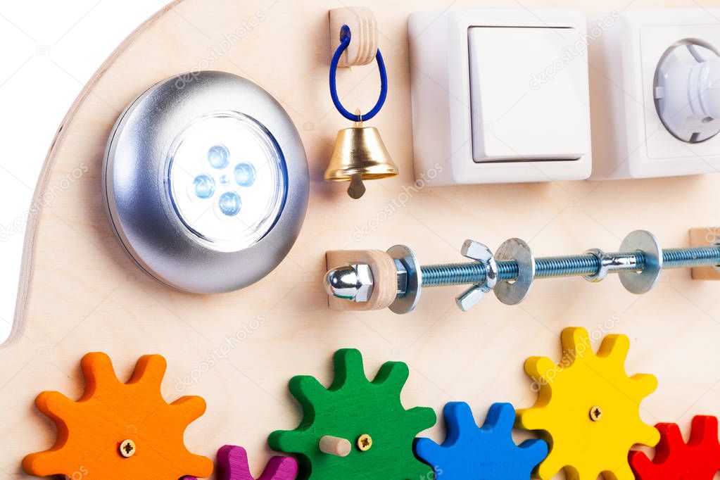 Wooden eco-friendly busy board - educational toy for children, babies on a white isolated background, consisting of a flashlight, a switch, beads, roller, bell, rosette.