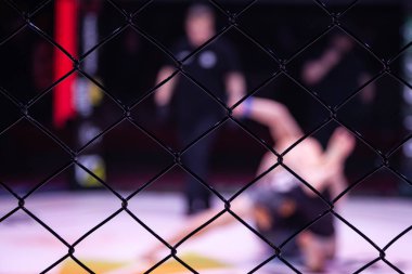 Kurallar olmadan mücadele spor kavramı. Sekizgen sahnenin arenasında iki atlet güreşçi. Boks kuralları mma olmadan Mood kavgalar. Metal kafes üzerinden spor savaşları alternatif bir bakış