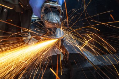 Yakın çekim parlak taraf anında açı kıyma makinesinden kıvılcım. Genç bir erkek kaynakçı bir beyaz eldiven çalışma açısı değirmeni garajda ile metal ürün biler