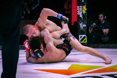 Novosibirsk, Rusya - 19 Nisan 2019: Salon of fam. Boxers dövüşçüleri, koyu renkli arka plandaki sirkte sekizgen halkada kuralsız dövüşlerde yerde güreştiler. Mma sürümüne göre kuralsız dövüşler