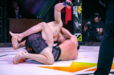 Novosibirsk, Rusya - 19 Nisan 2019: Salon of fam. Boxers dövüşçüleri, koyu renkli arka plandaki sirkte sekizgen halkada kuralsız dövüşlerde yerde güreştiler. Mma sürümüne göre kuralsız dövüşler