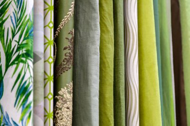 Close-up rows of pieces of fabric made of cotton, polyester, tapestry and other materials of different colors and prints for sewing curtains, bedding and clothing clipart