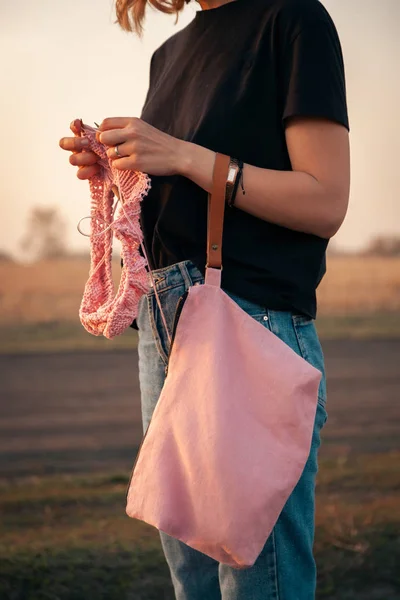 自然なウールの糸からピンクの汗をかいて編み物をして微笑む若い美しい黒髪の女性の屋外の大気のライフスタイルの写真 — ストック写真