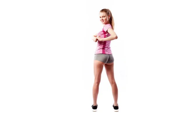 一个年轻的苗条女运动员在运动粉红色的上衣和短裤使转一边 在工作室的白色孤立背景 后视图 一个美丽的女运动员的肖像 — 图库照片