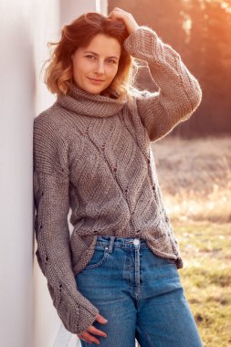 Örgü şapka ve sıcak giysiler güzel bir genç model Portresi güneşli sonbahar gününde arka plan alanında, gün keyfini çıkarın. Sonbahar sıcak fotoğraf. 