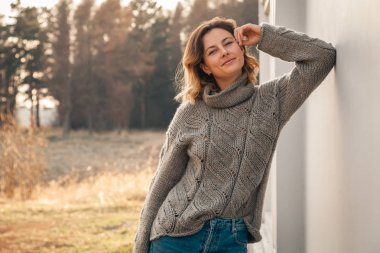 Sonbahar alan manzara kahverengi örgü kazak ve kot genç güzel kadın Açık moda fotoğraf. Moda lookbook. 
