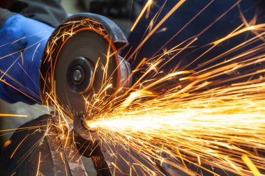 Yakın çekim parlak taraf anında açı kıyma makinesinden kıvılcım. Genç bir erkek kaynakçı bir beyaz eldiven çalışma açısı değirmeni garajda ile metal ürün biler