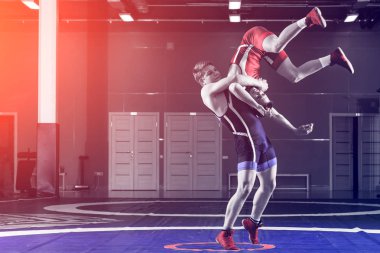 Adil güreş kavramı. Spor salonunda güreş halısında kırmızı ve mavi üniformalı iki greko-romen güreşçi güreş. Adil güreş kavramı