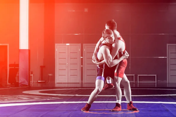 The concept of fair wrestling. Two greco-roman  wrestlers in red and blue uniform wrestling   on a wrestling carpet in the gym