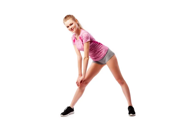 运动在白色背景 健身概念 一个穿着舒适运动服 短裤和上衣 的年轻女子微笑着 在偏僻的白色背景上用双腿向两侧做宽阔的大腿 — 图库照片