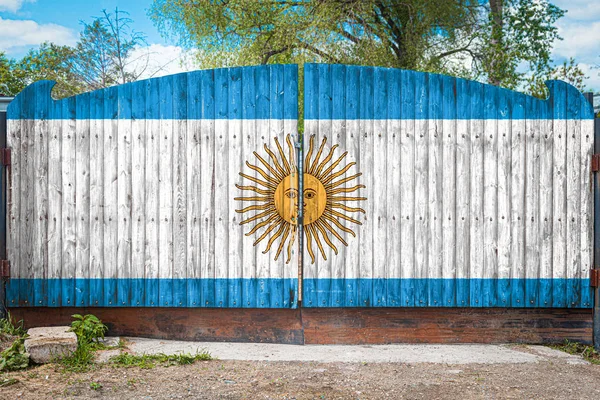 Close-up of the national flag of Argentina on a wooden gate at the entrance to the closed territory on a summer day. The concept of storage of goods, entry to a closed area, tourism in Argentina