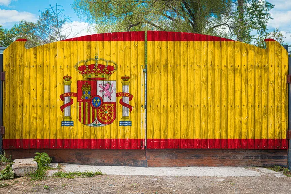 Close-up of the national flag of Spain on a wooden gate at the entrance to the closed territory on a summer day. The concept of storage of goods, entry to a closed area, tourism in Spain