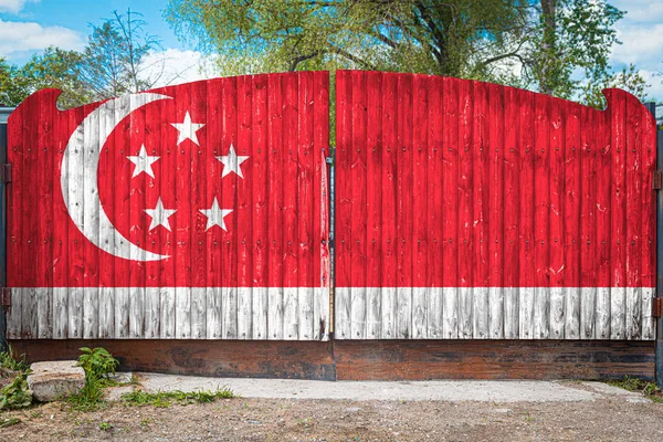 Close-up of the national flag of Singapore on a wooden gate at the entrance to the closed territory on a summer day. The concept of storage of goods, entry to a closed area, tourism in Singapore