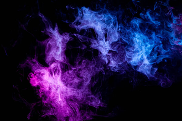 Thick colorful smoke of pink, blue on a black isolated background. Background from the smoke of vap