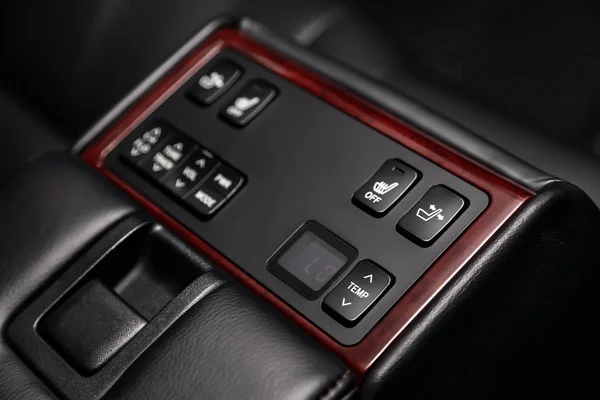 close-up of the car  black interior:   seat heatting and adjustment  buttons,  temperature regulator and other buttons. Soft focus