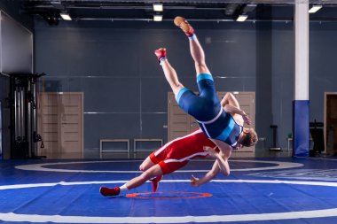 Mavi ve kırmızı güreş tayt iki genç adam wrestlng ve spor salonunda bir güreş halı üzerinde bir suplex güreş yapıyor