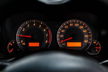 Siyah salonlu arabanın iç görünümü. Modern lüks prestij araba iç: hız göstergesi, gösterge paneli ve sarı arka ışık ve diğer düğmeleri ile takometre. Yumuşak odaklama 