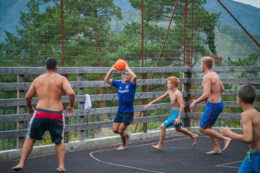 Altay, Rusya 08 Ağustos 2018: Sıcak bir yaz gününde dağlardaki bir çocuk kampında basketbol sahasında basketbol oynayan gençler 
